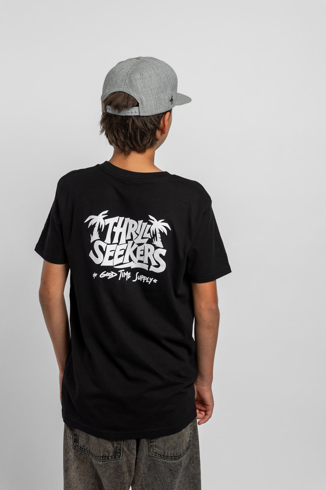 Kid wearing black tee with 'Thrill Seekers' good time supply logo in white