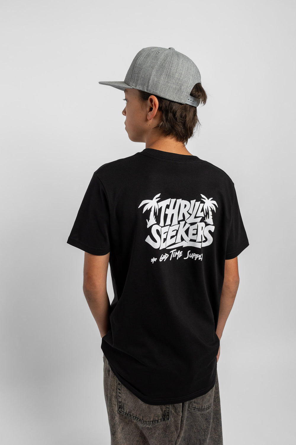 Kid wearing black tee with 'Thrill Seekers' good time supply logo in white