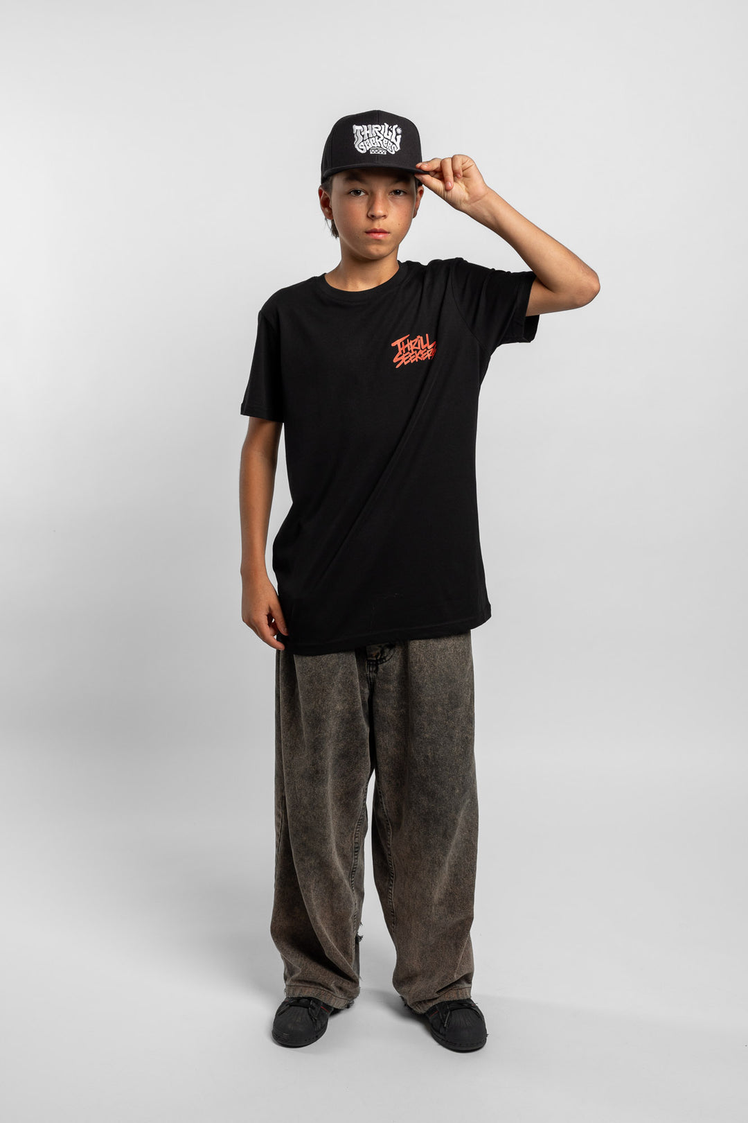 Kid wearing a black tee with 'Thrill Seekers' logo in cardinal red