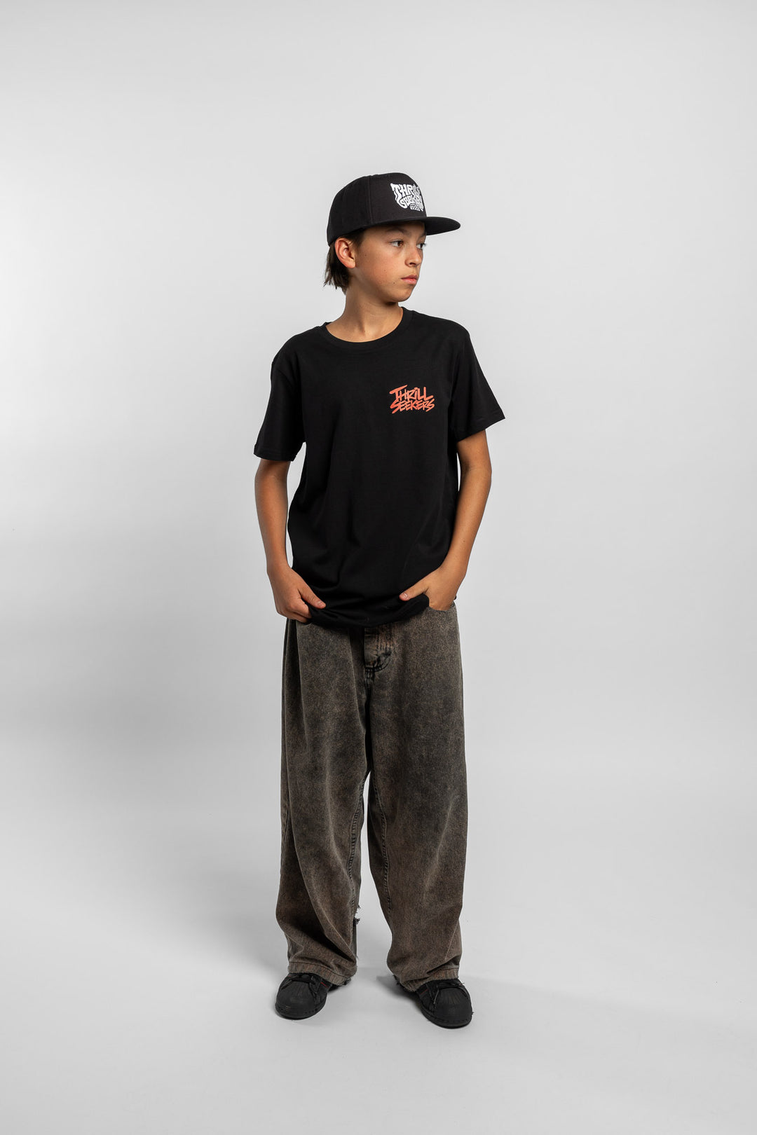 Kid wearing a black tee with 'Thrill Seekers' logo in cardinal red