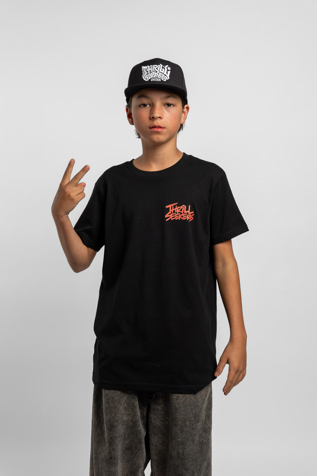 Kid wearing a black tee with 'Thrill Seekers' logo in cardinal red
