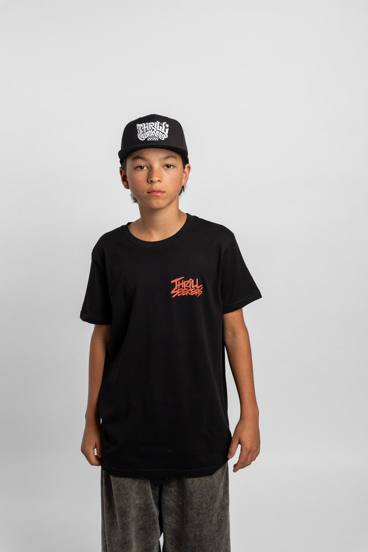 Kid wearing a black tee with 'Thrill Seekers' logo in cardinal red