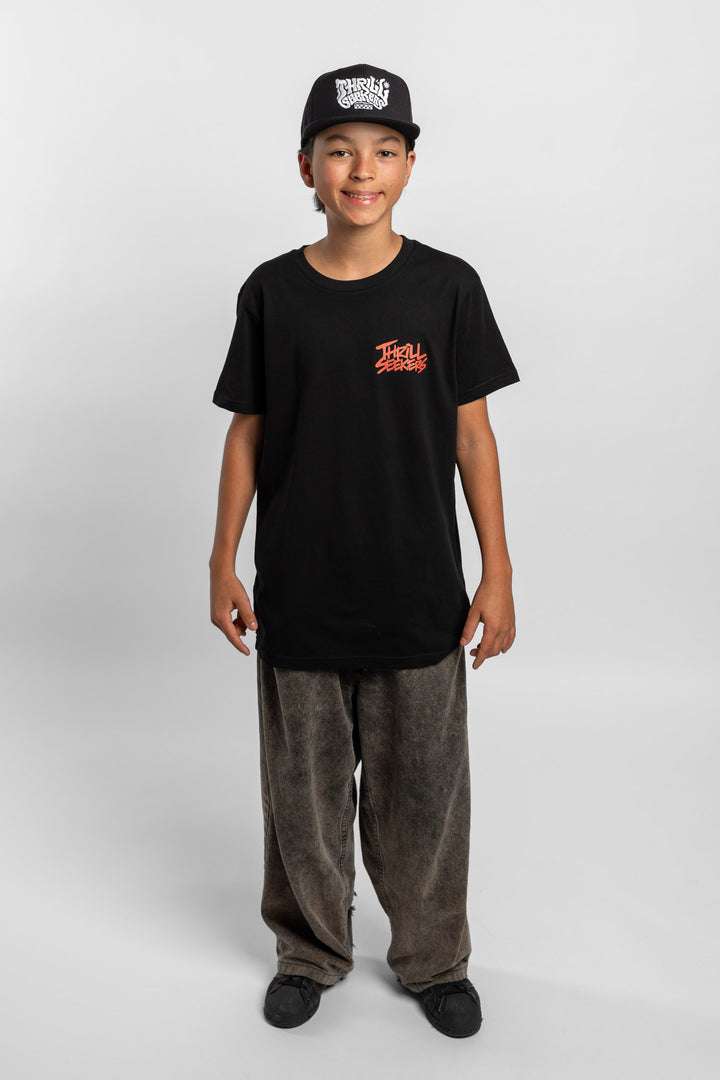 Kid wearing a black tee with 'Thrill Seekers' logo in cardinal red