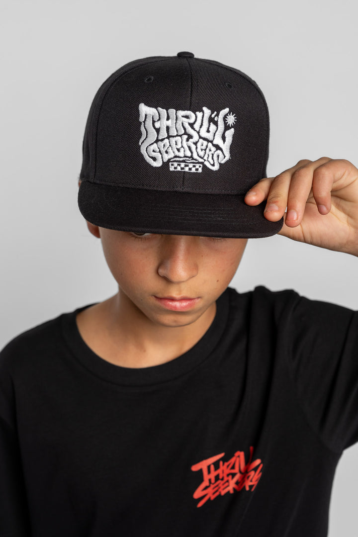 Person wearing a black cap with 'Thrill Seekers' logo on a white background