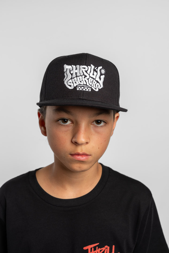 Person wearing a black cap with 'Thrill Seekers' logo on a white background