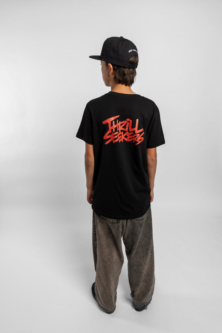 Kid wearing a black tee with 'Thrill Seekers' logo in cardinal red