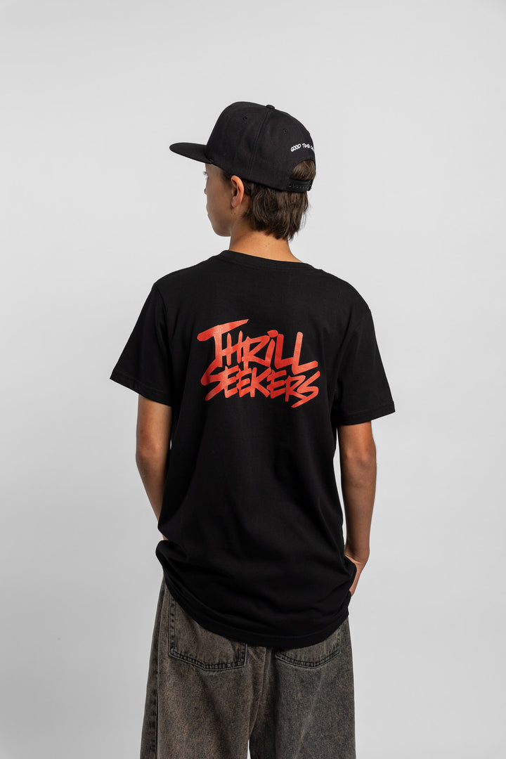 Kid wearing a black tee with 'Thrill Seekers' logo in cardinal red