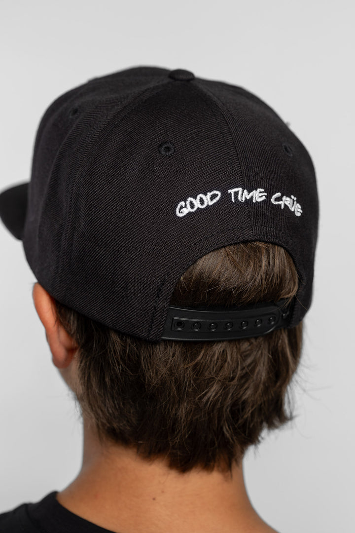 Back of a black cap with 'Good Time Crue' text on a person with a white background