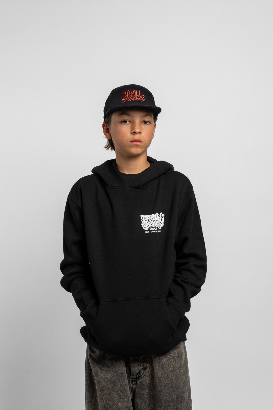 Kid wearing black hoodie with 'Thrill Seekers' smokin' logo in black