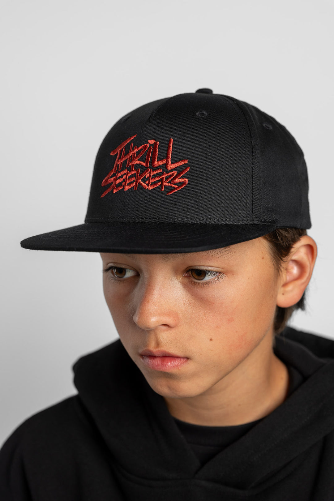 Person wearing a black cap with cardinal red text on a white background