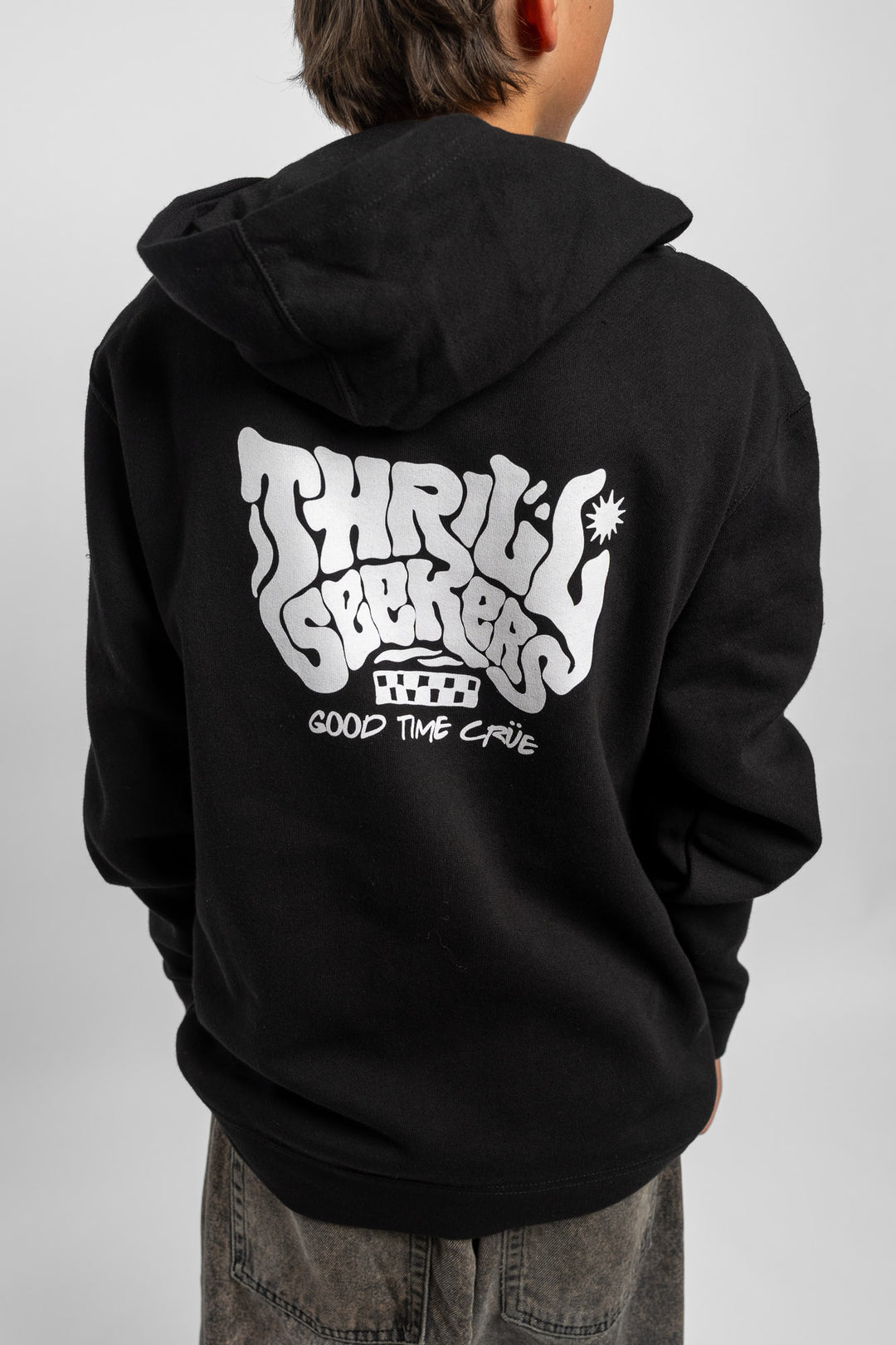 Kid wearing black hoodie with 'Thrill Seekers' smokin' logo in black