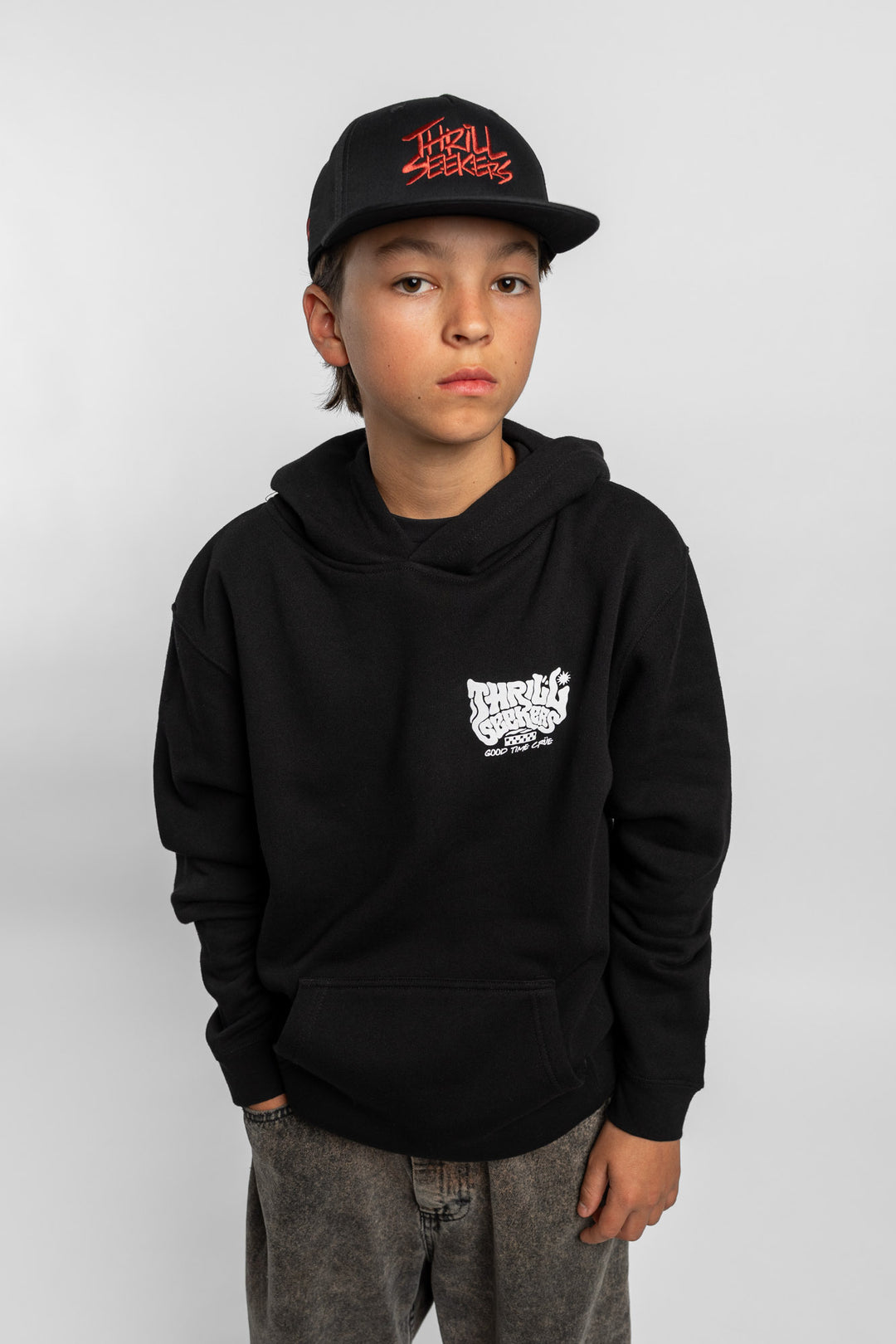 Kid wearing black hoodie with 'Thrill Seekers' smokin' logo in black