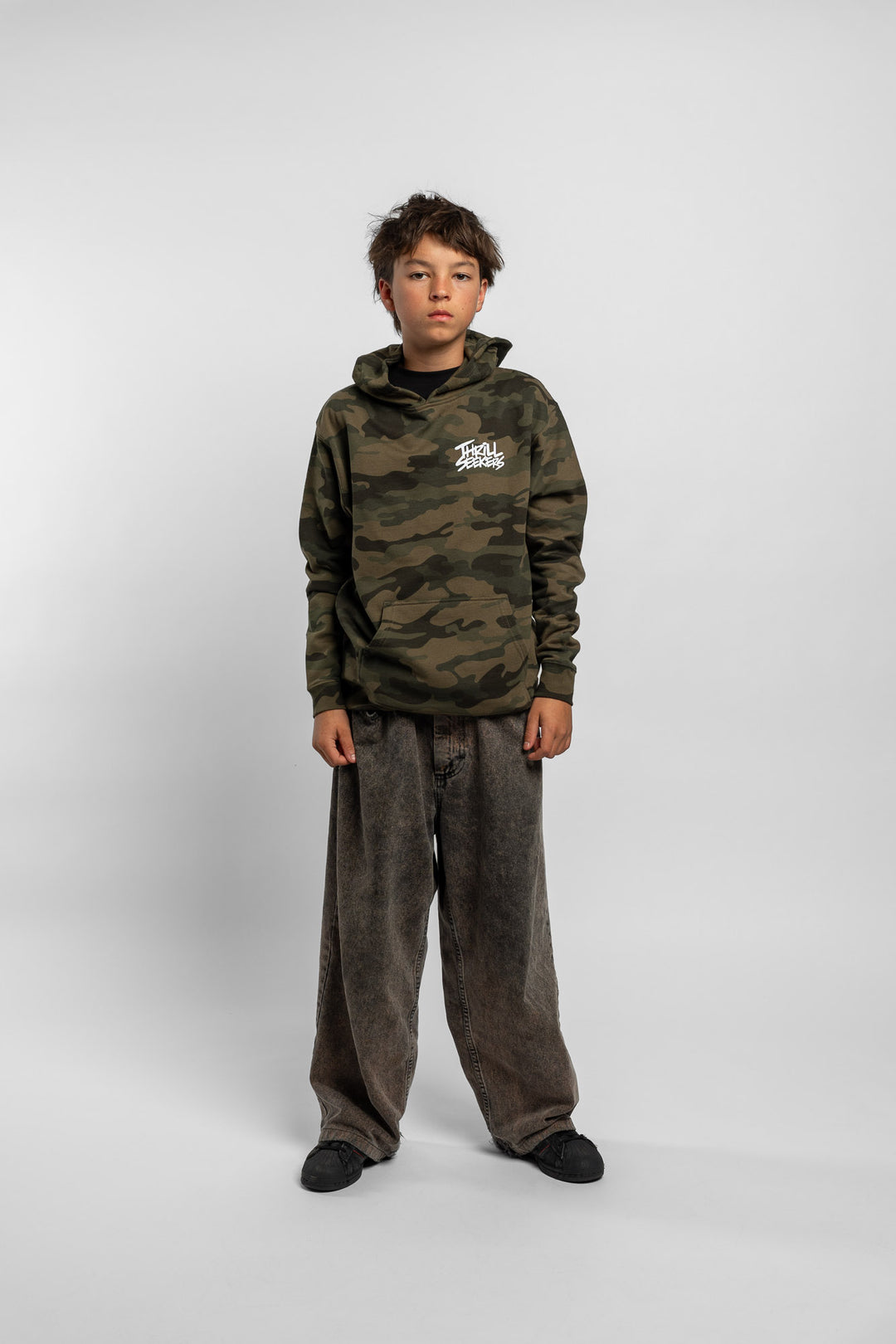 Kid wearing a camo hoodie with 'Thrill Seekers' logo in white