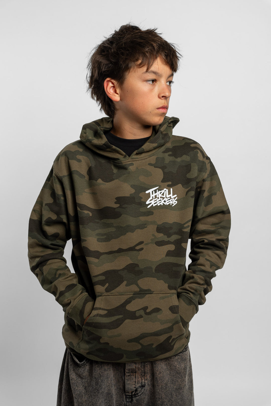 Kid wearing a camo hoodie with 'Thrill Seekers' logo in white