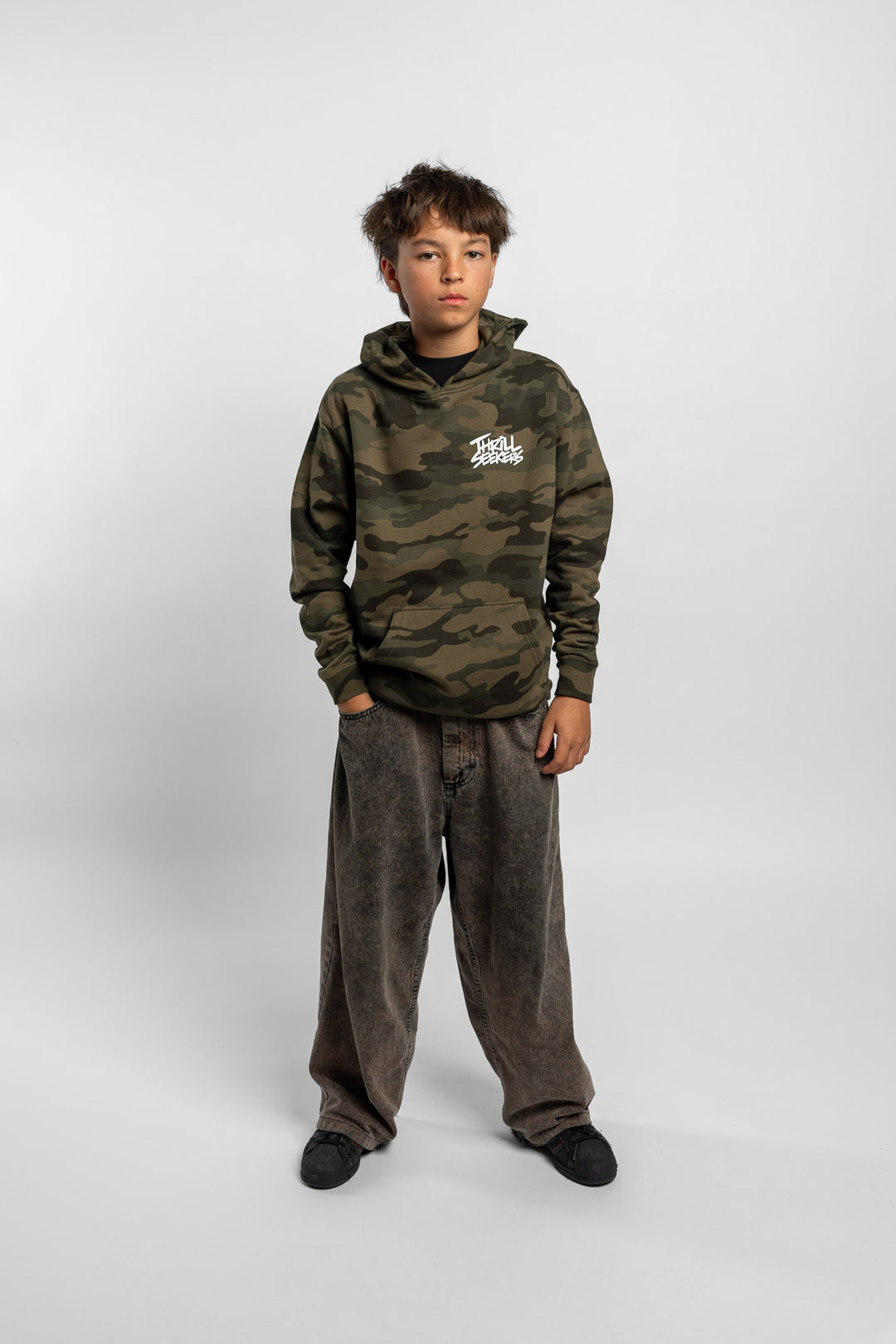 Kid wearing a camo hoodie with 'Thrill Seekers' logo in white