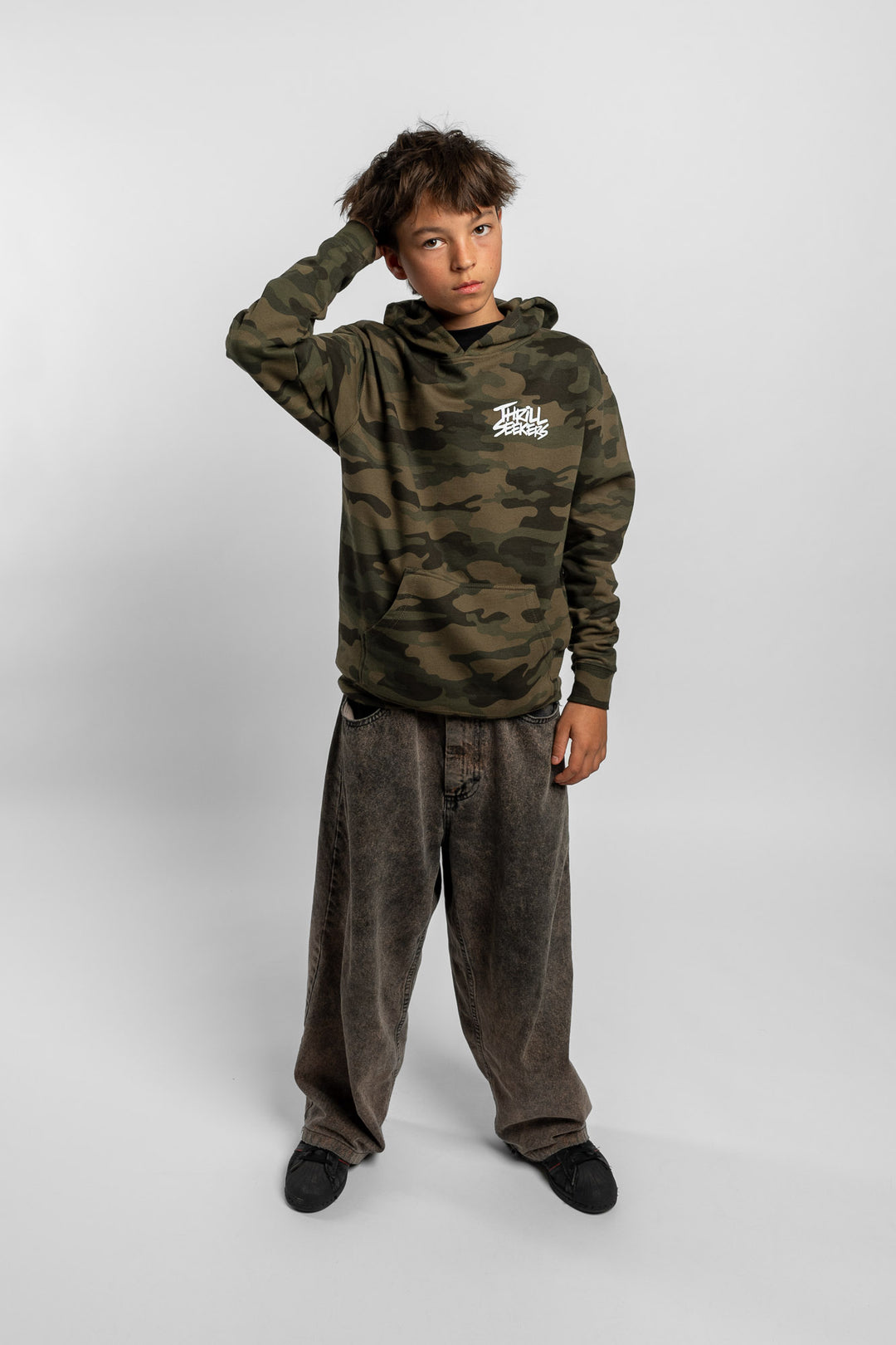 Kid wearing a camo hoodie with 'Thrill Seekers' logo in white