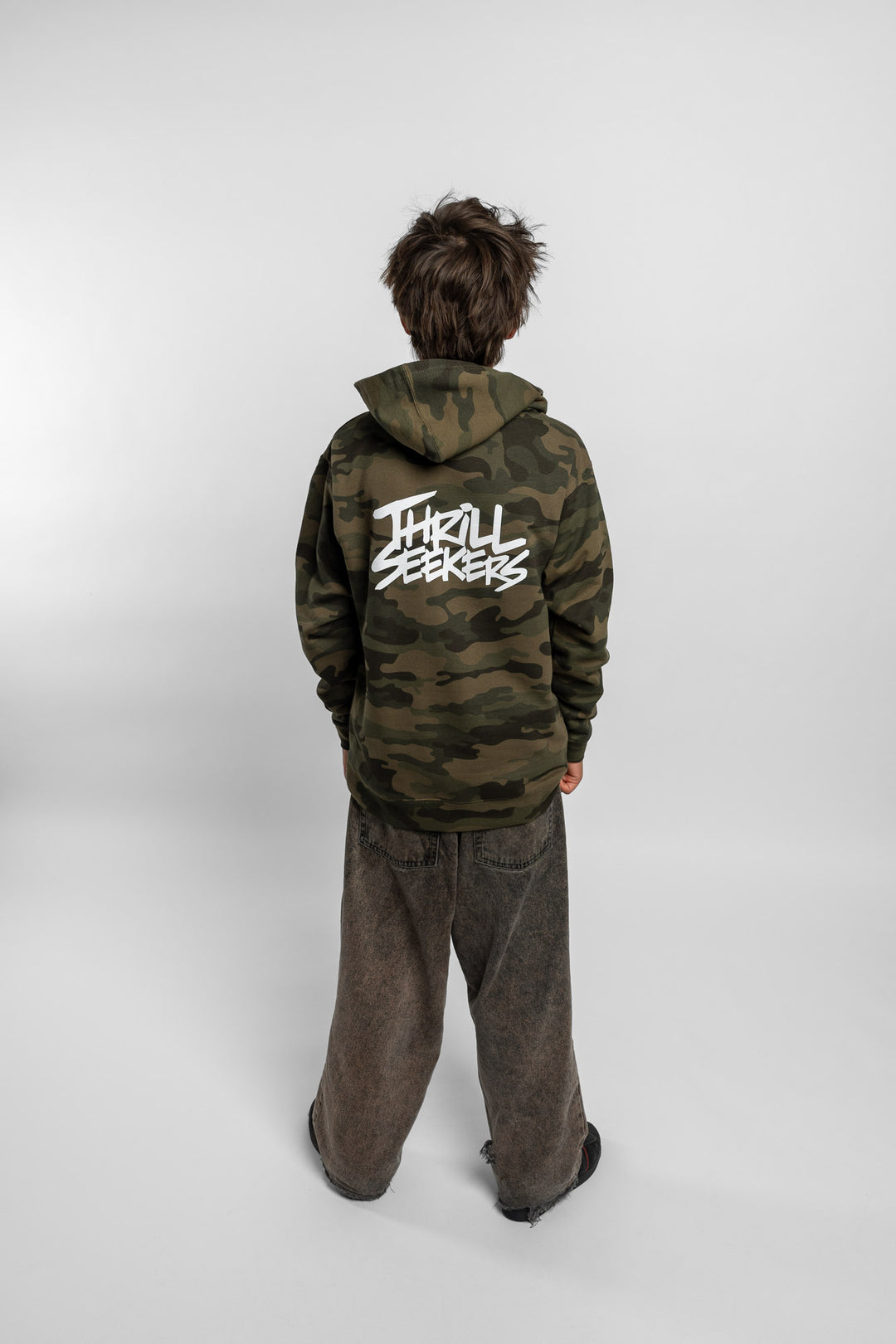 Kid wearing a camo hoodie with 'Thrill Seekers' logo in white