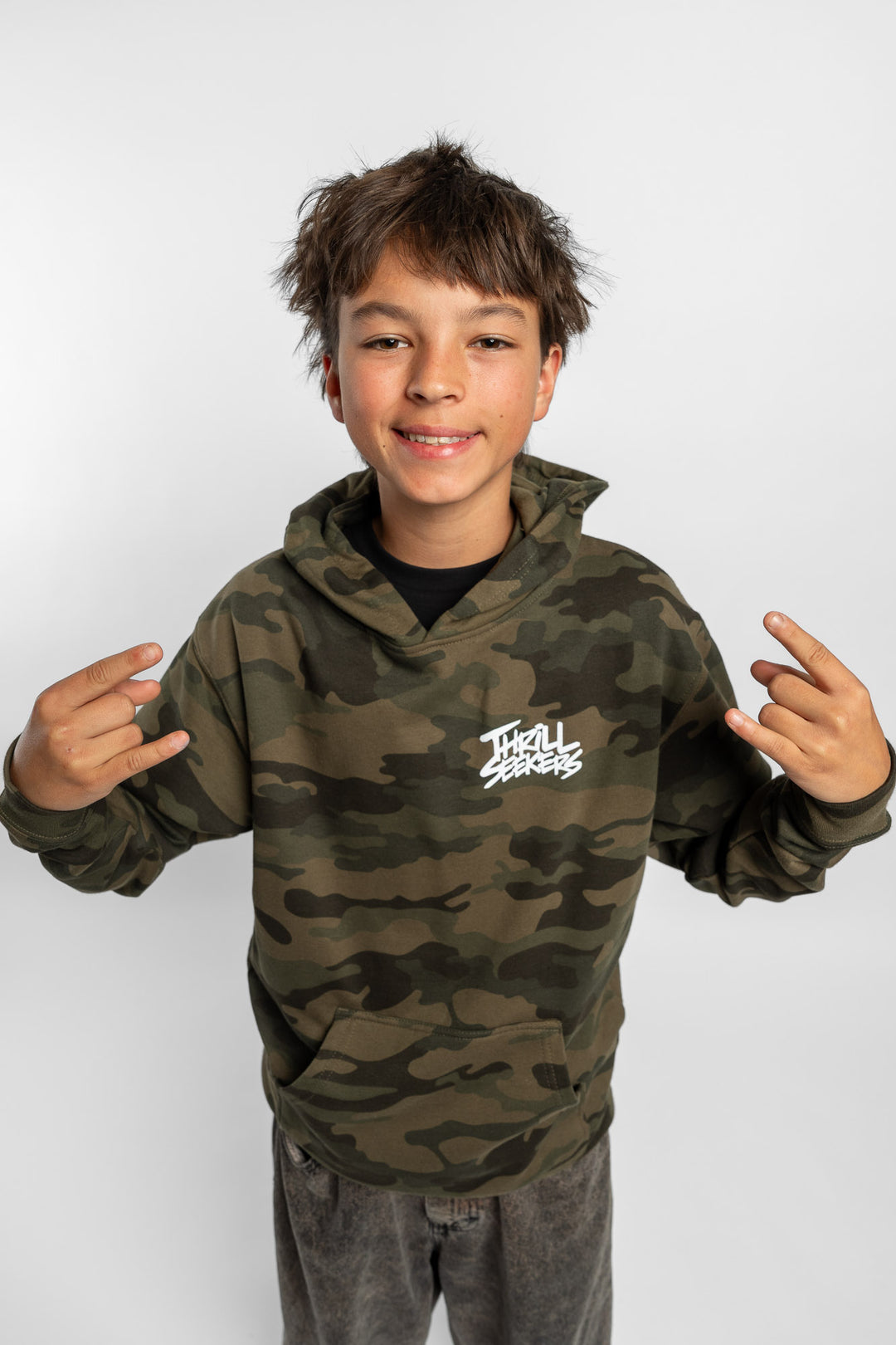 Kid wearing a camo hoodie with 'Thrill Seekers' logo in white