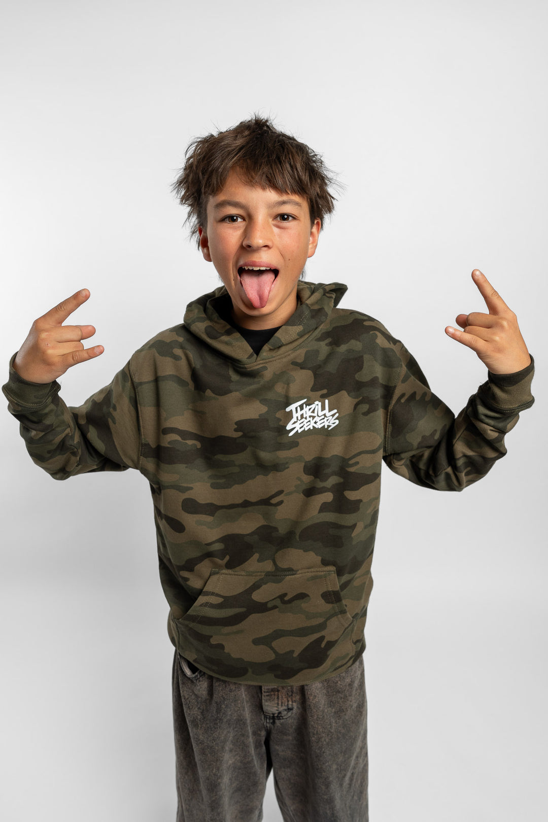 Kid wearing a camo hoodie with 'Thrill Seekers' logo in white