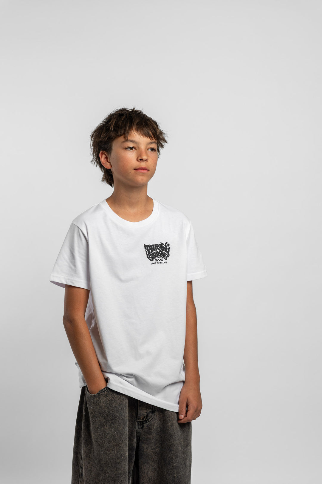 Kid wearing a white tee with 'Thrill Seekers' smokin logo in black