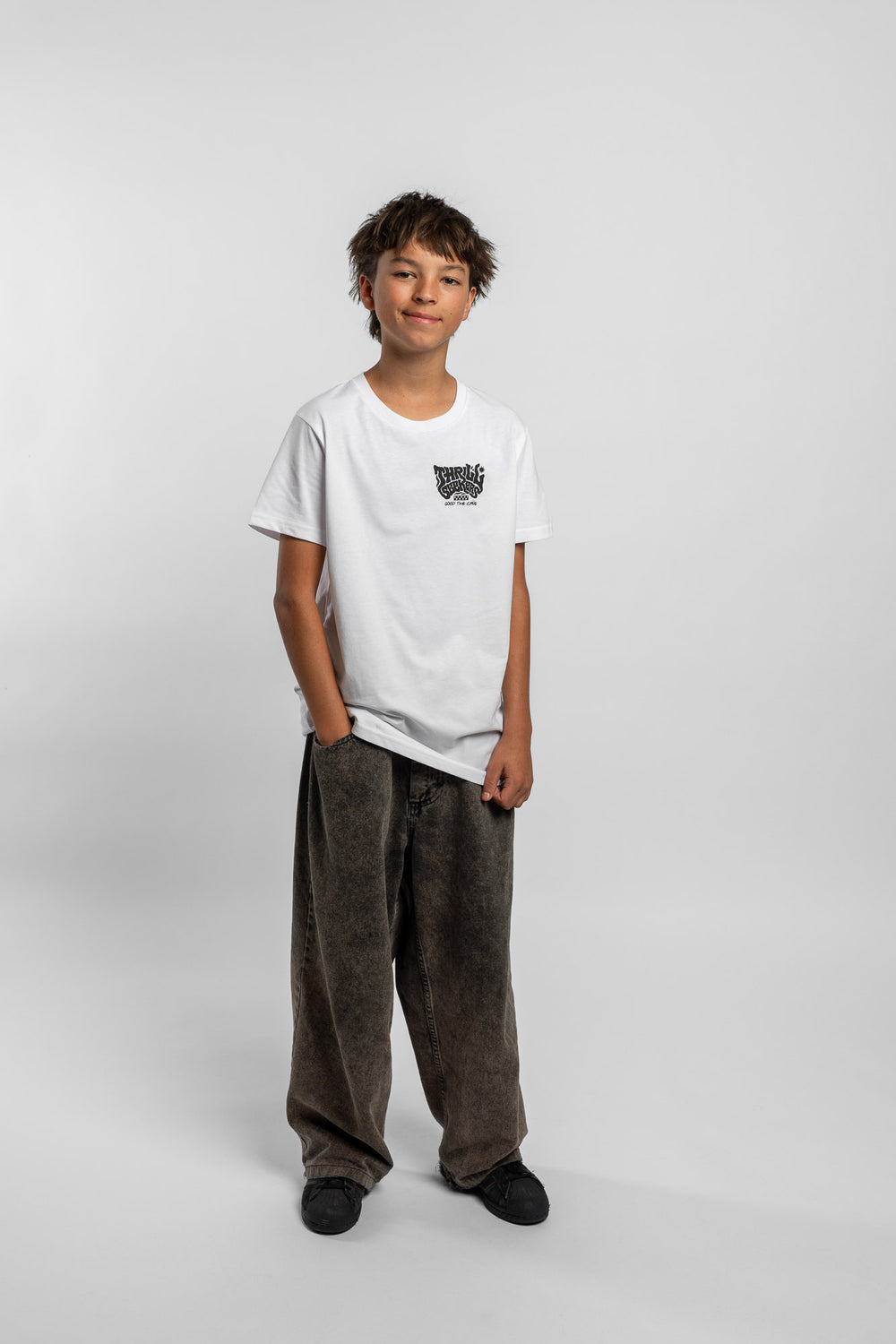 Kid wearing a white tee with 'Thrill Seekers' smokin logo in black