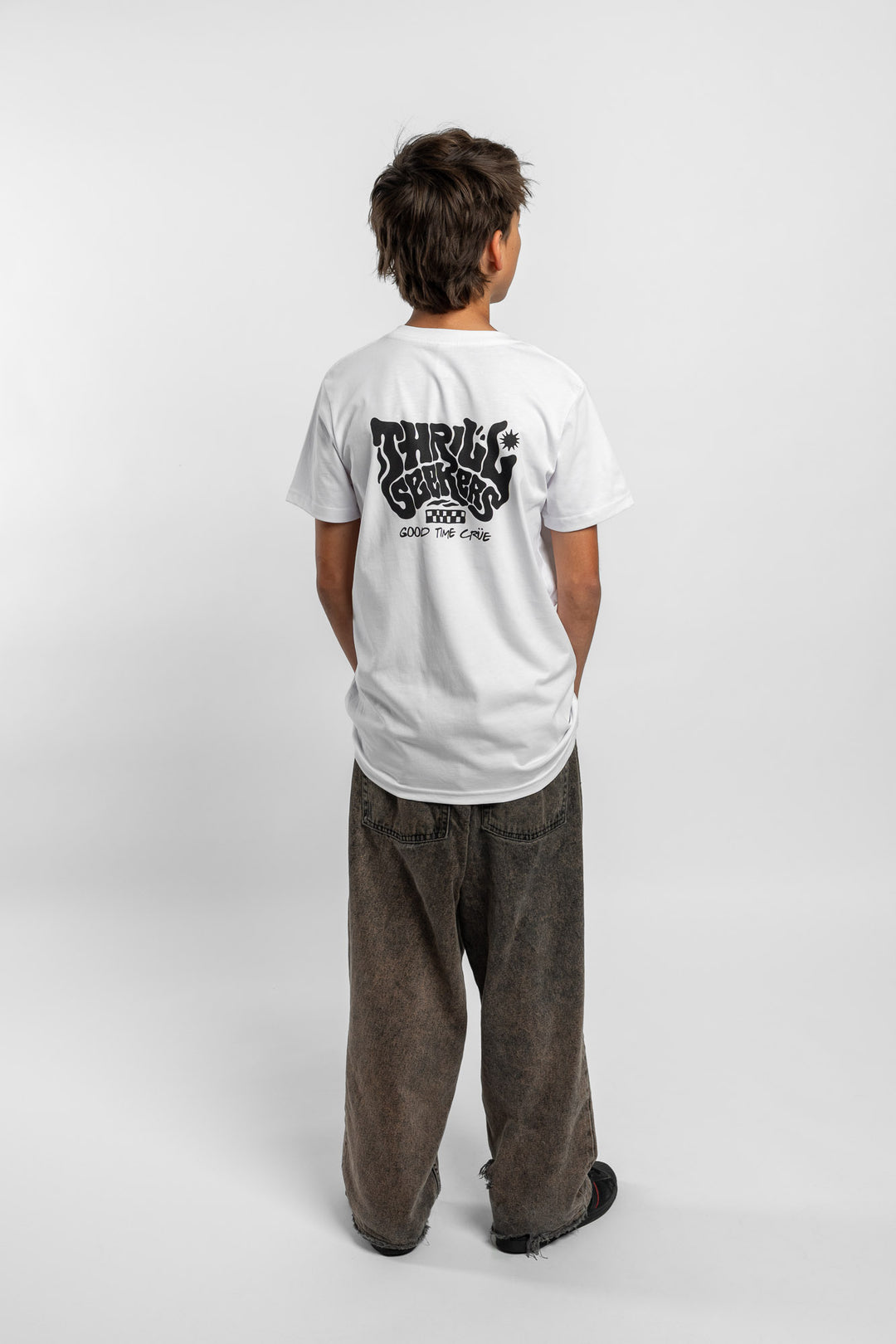 Kid wearing a white tee with 'Thrill Seekers' smokin logo in black