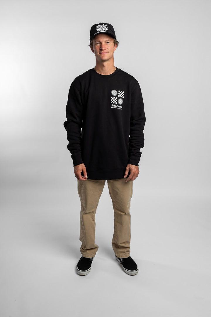 Person wearing a black crewneck with a 'Thrill Seekers' tile logo