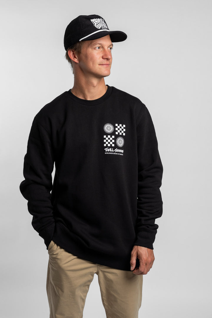 Person wearing a black crewneck with a 'Thrill Seekers' tile logo