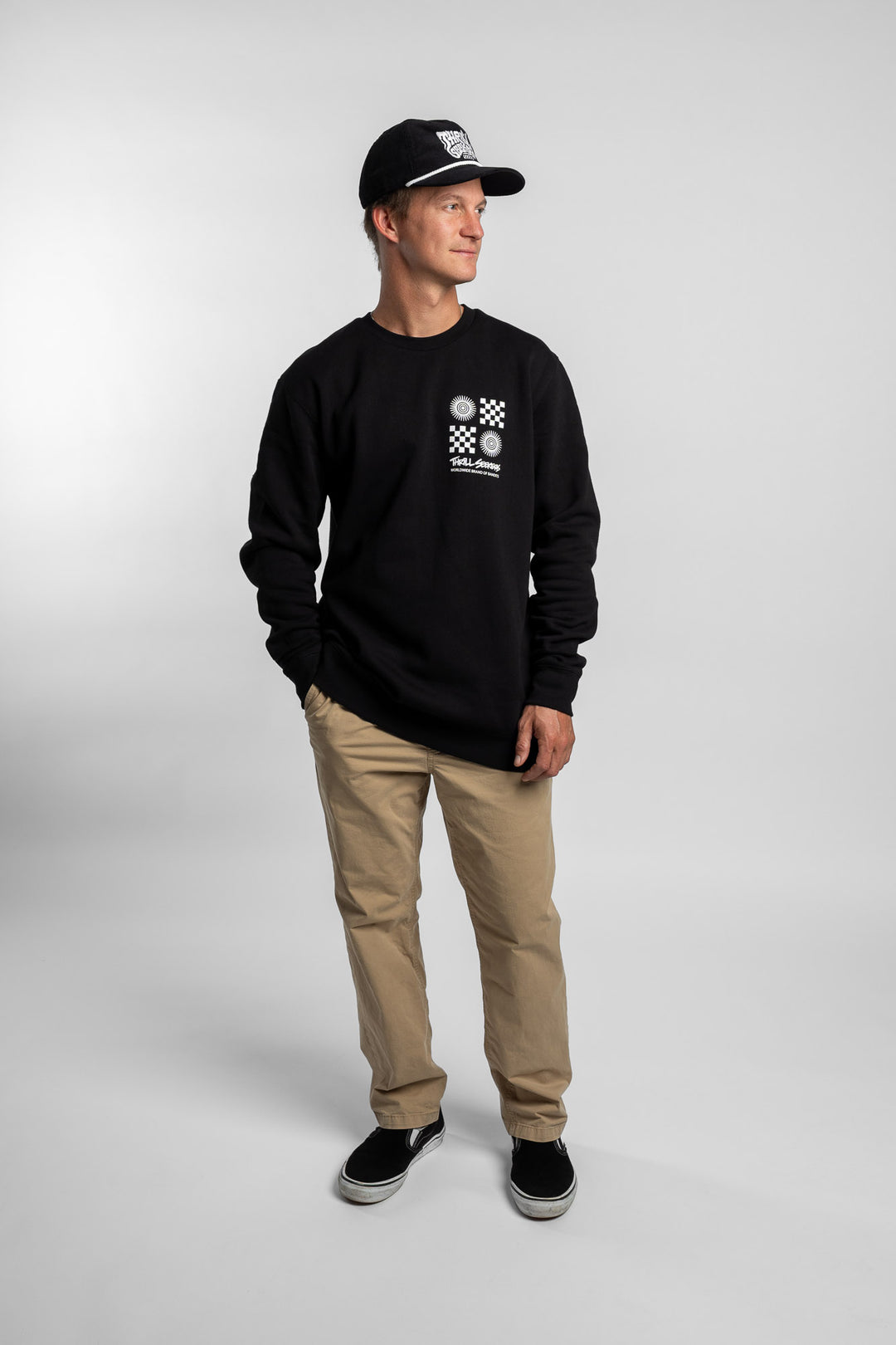 Person wearing a black crewneck with a 'Thrill Seekers' tile logo
