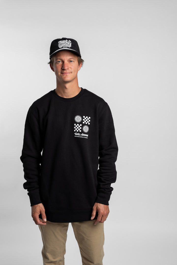 Person wearing a black crewneck with a 'Thrill Seekers' tile logo