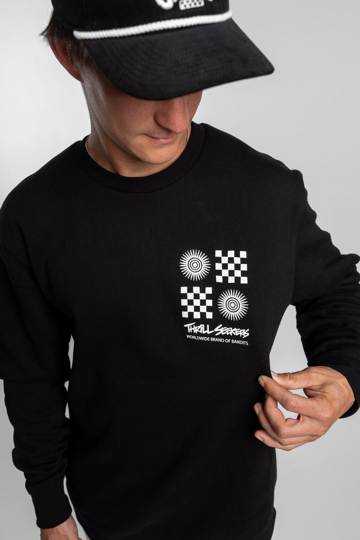 Person wearing a black crewneck with a 'Thrill Seekers' tile logo
