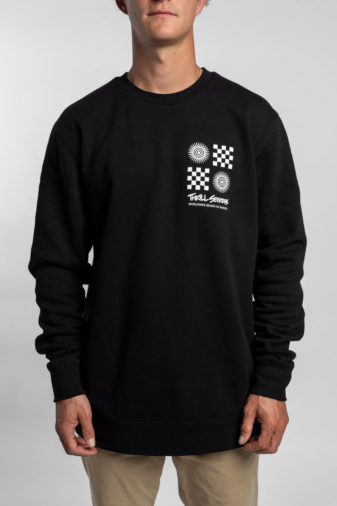 Person wearing a black crewneck with a 'Thrill Seekers' tile logo