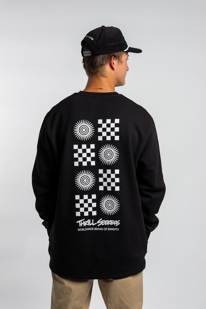 Person wearing a black crewneck with a 'Thrill Seekers' tile logo