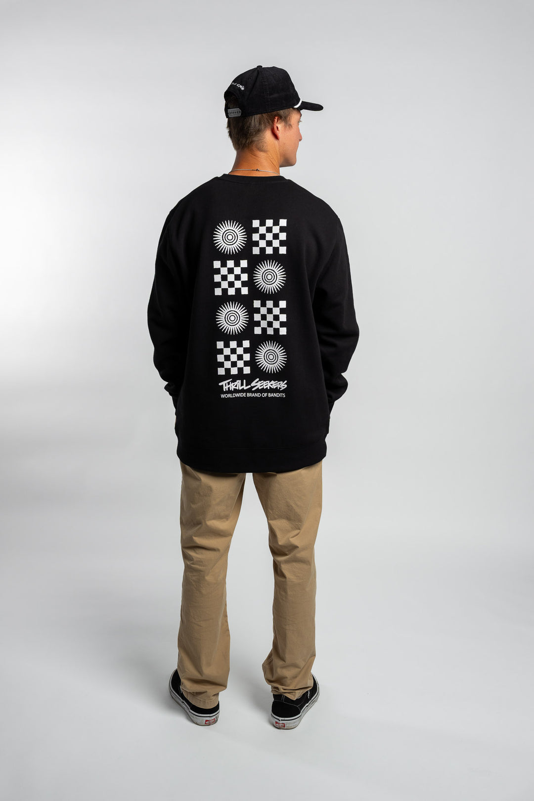 Person wearing a black crewneck with a 'Thrill Seekers' tile logo