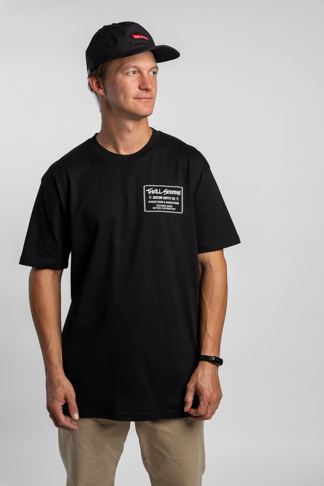 Person wearing black tee with 'Thrill Seekers' workman logo in white
