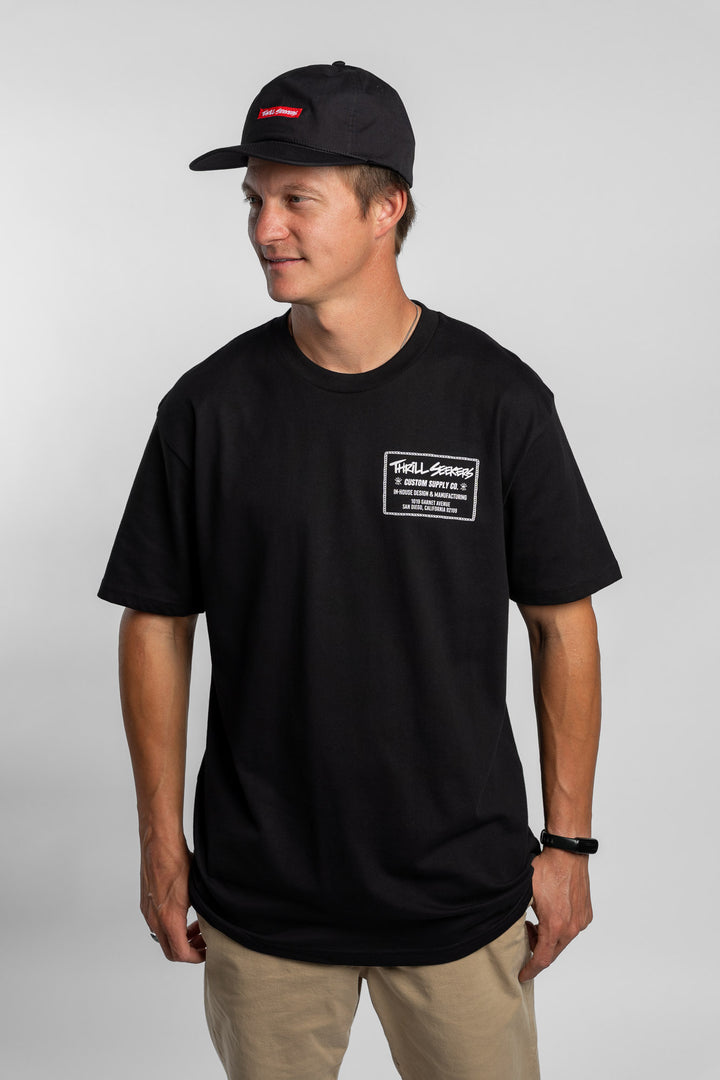 Person wearing black tee with 'Thrill Seekers' workman logo in white