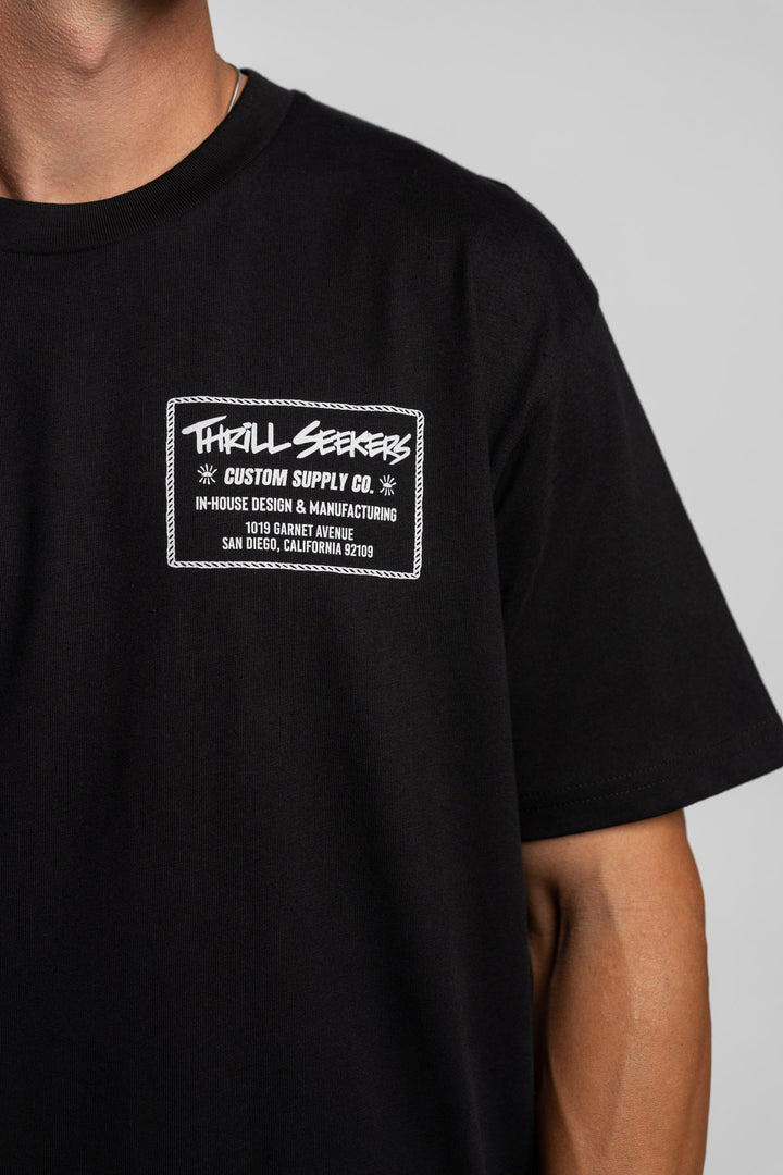 Person wearing black tee with 'Thrill Seekers' workman logo in white