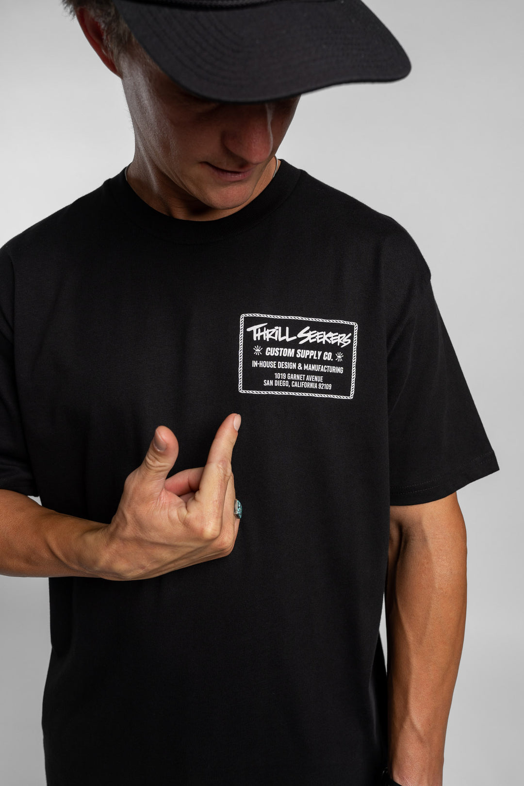 Person wearing black tee with 'Thrill Seekers' workman logo in white
