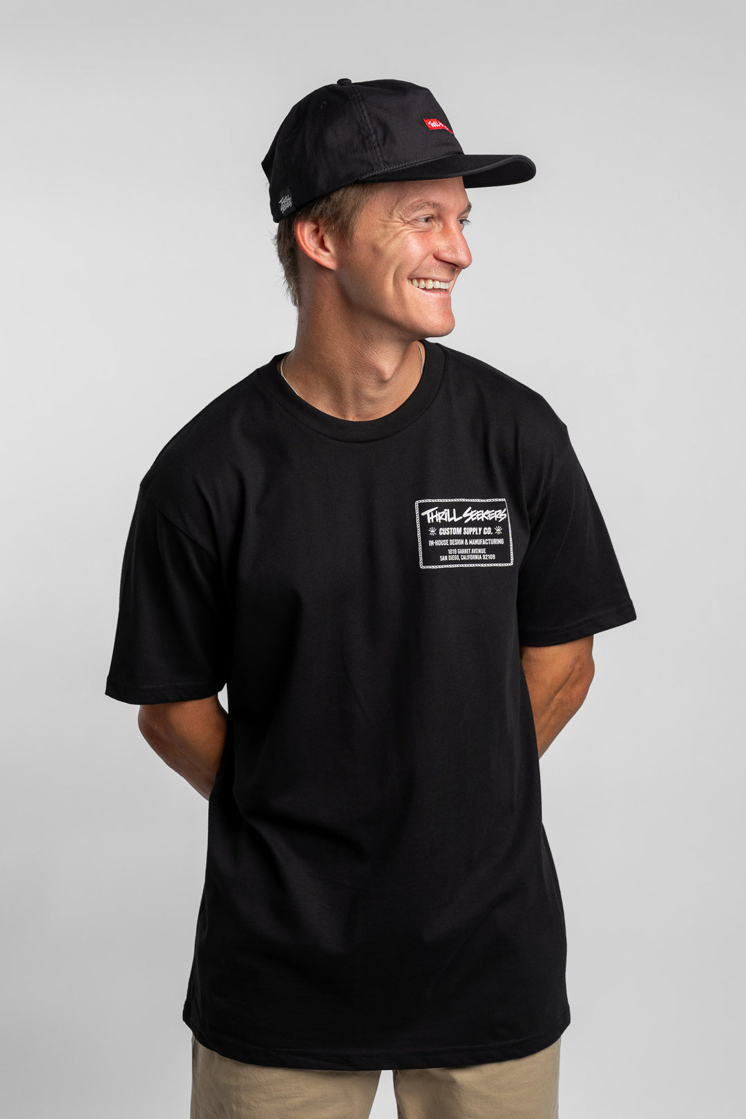 Person wearing black tee with 'Thrill Seekers' workman logo in white