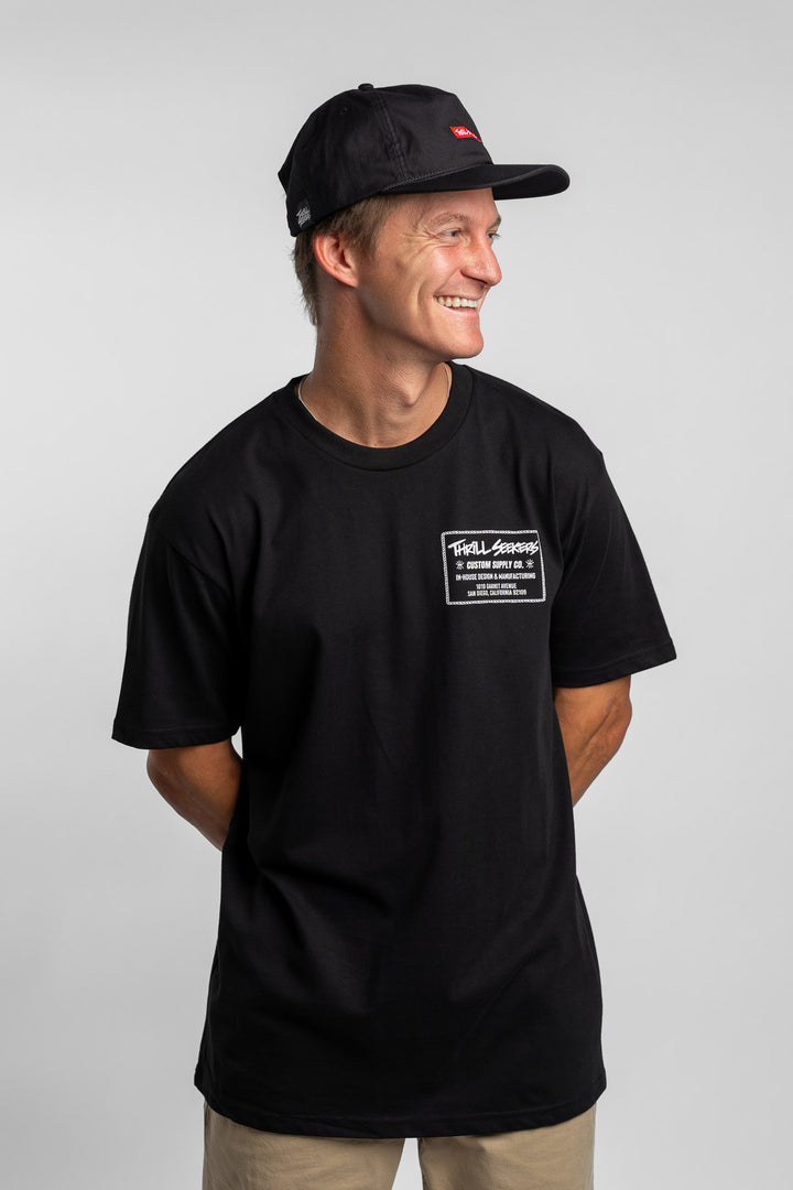 Person wearing black tee with 'Thrill Seekers' workman logo in white