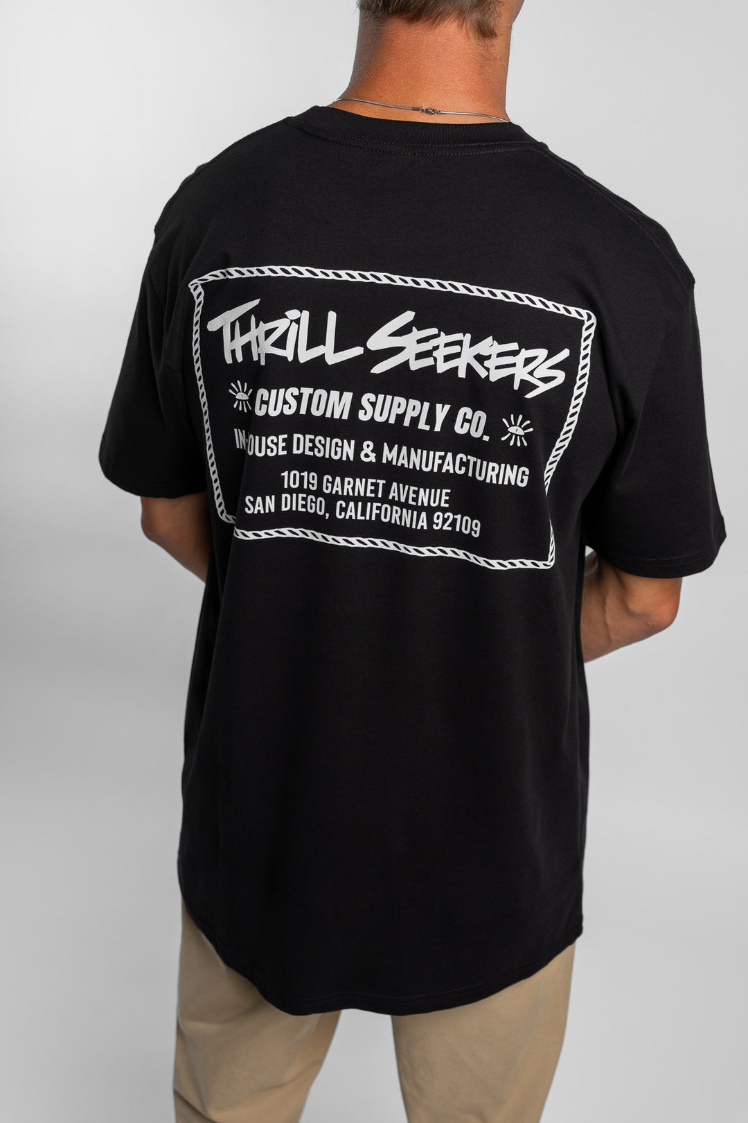 Person wearing black tee with 'Thrill Seekers' workman logo in white