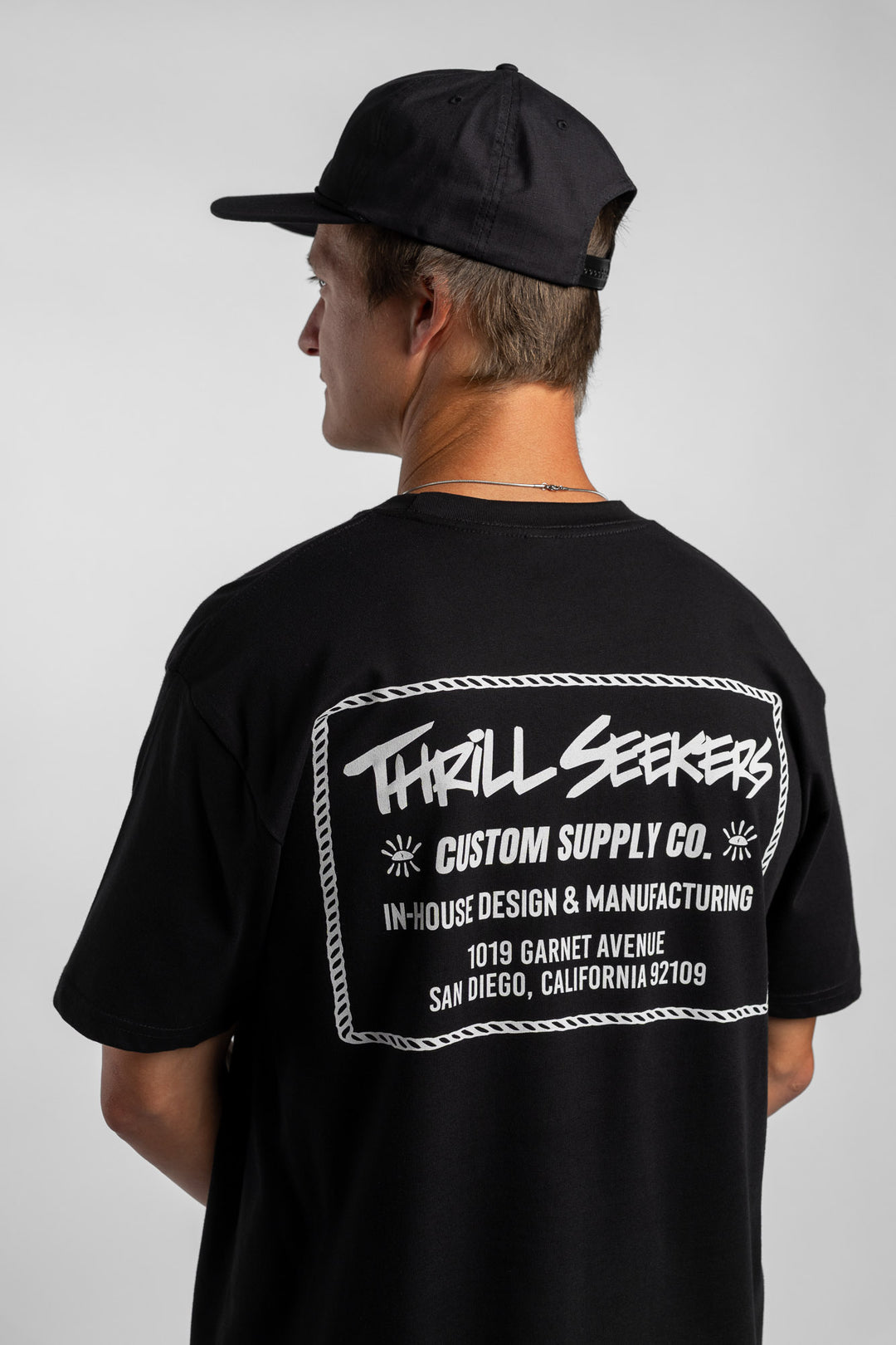 Person wearing black tee with 'Thrill Seekers' workman logo in white