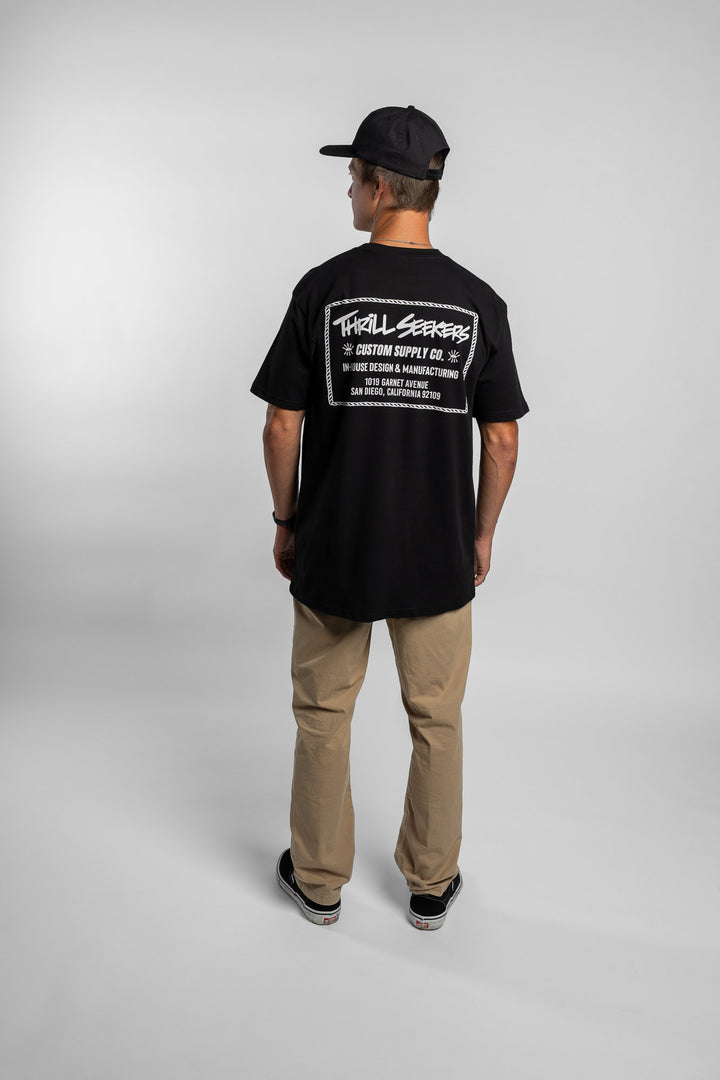 Person wearing black tee with 'Thrill Seekers' workman logo in white