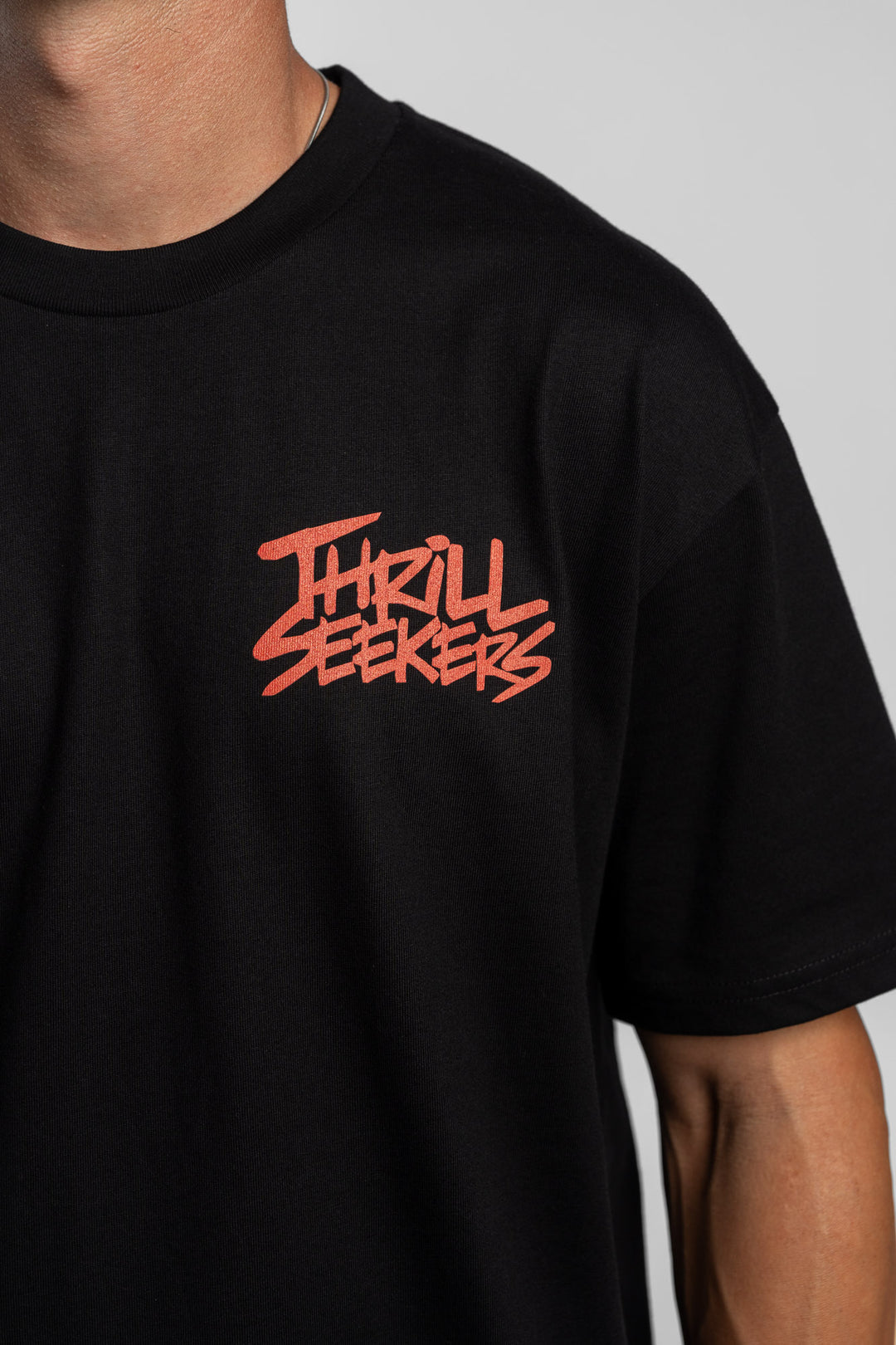 Person wearing a black tee with a 'Thrill Seekers' logo in cardinal red