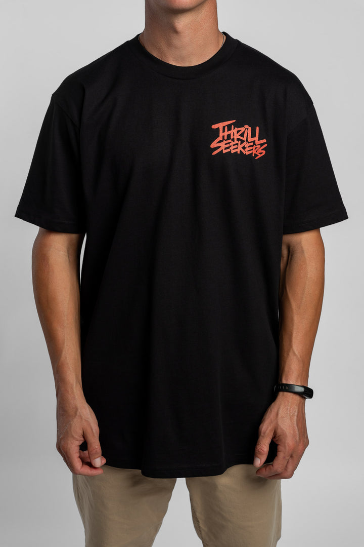 Person wearing a black tee with a 'Thrill Seekers' logo in cardinal red