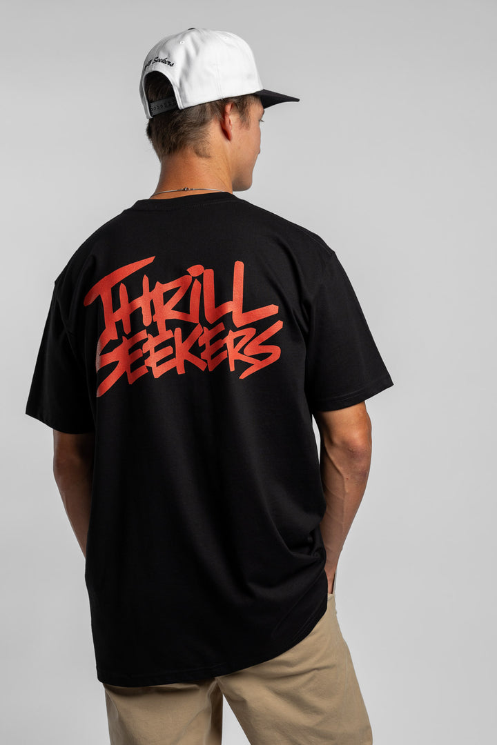 Person wearing a black tee with a 'Thrill Seekers' logo in cardinal red