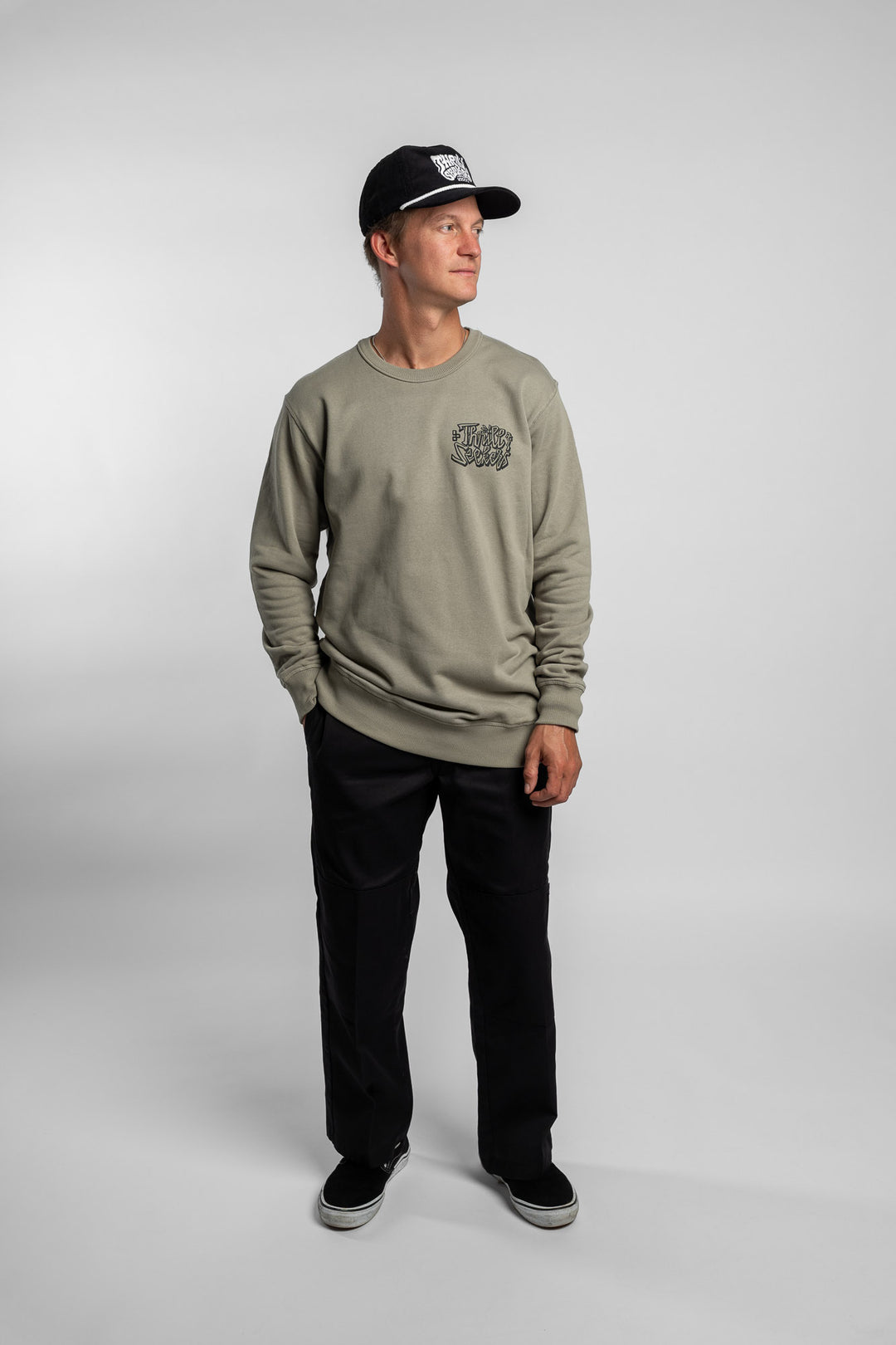 Person wearing eucalyptus crewneck with 'Thrill Seekers' scribe logo