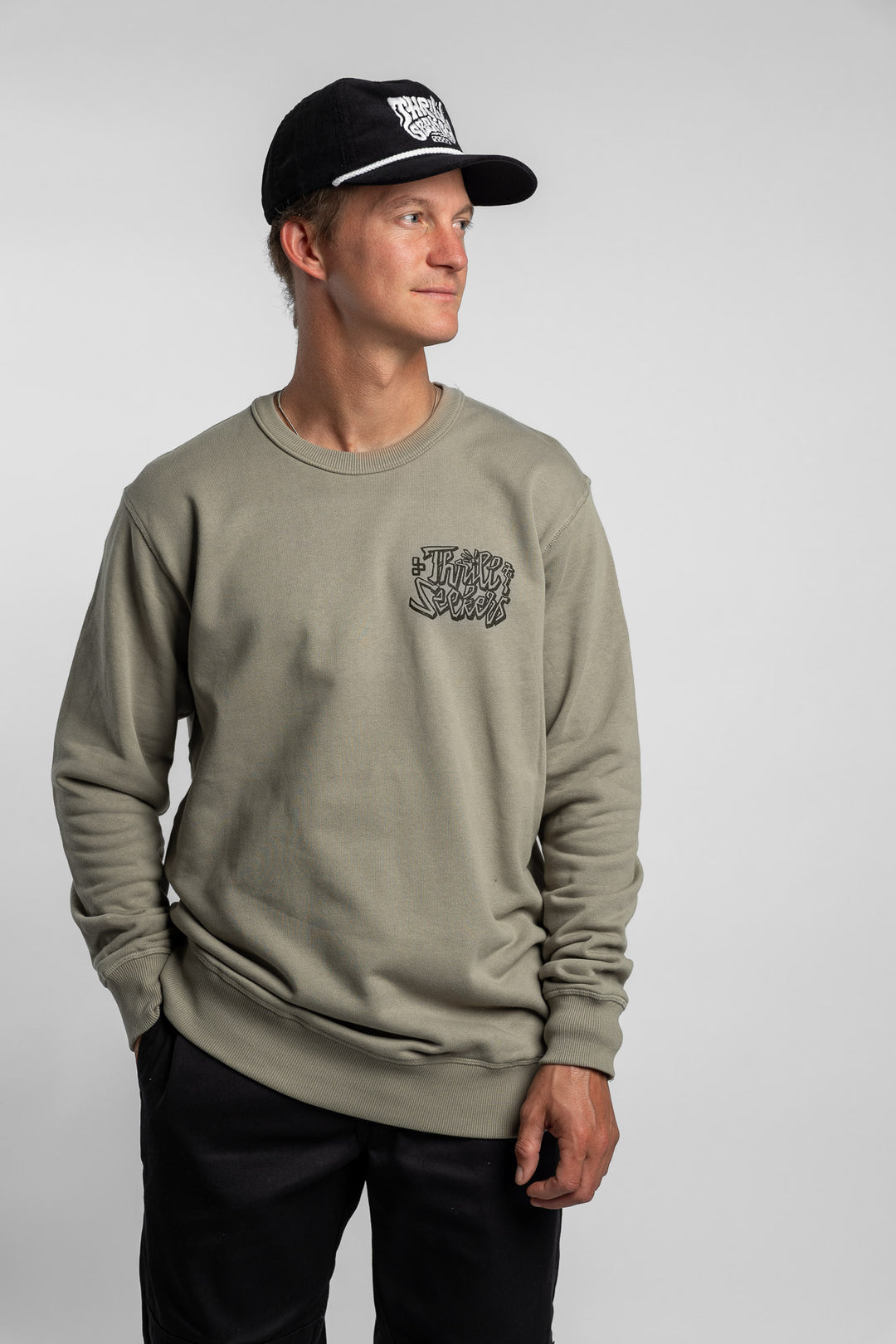 Person wearing eucalyptus crewneck with 'Thrill Seekers' scribe logo