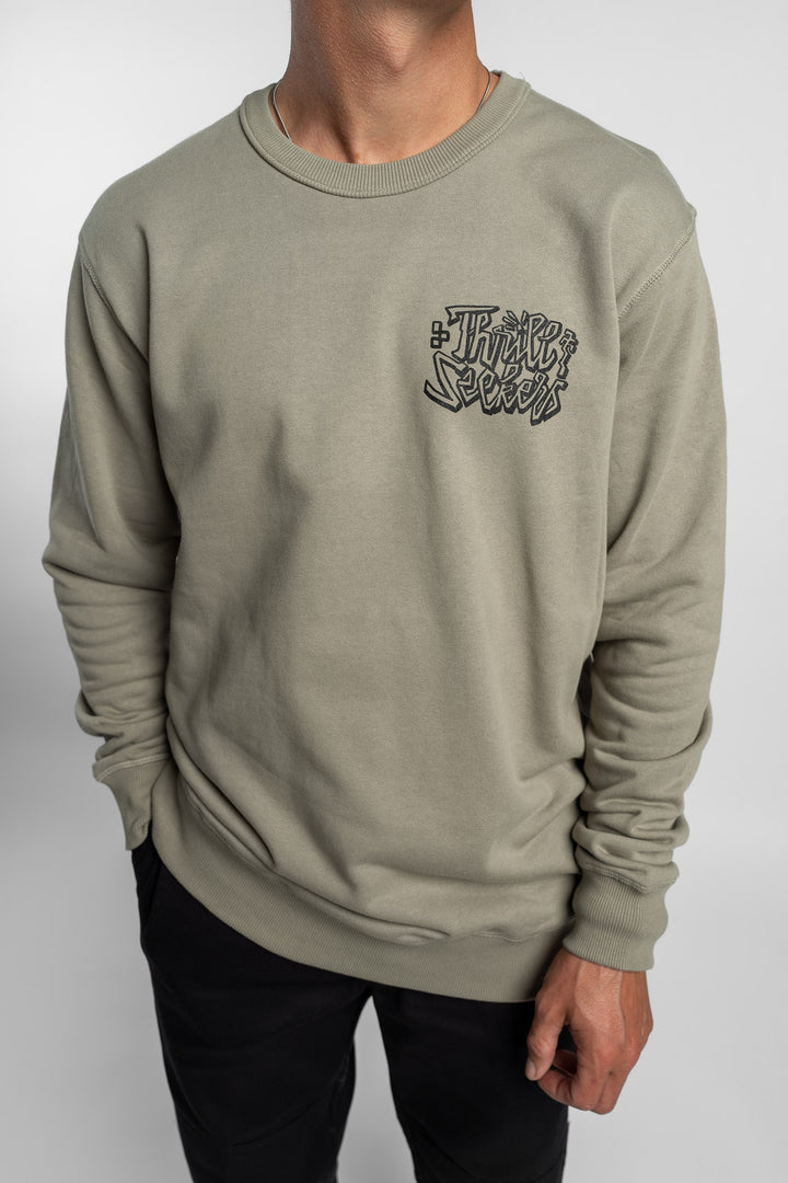 Person wearing eucalyptus crewneck with 'Thrill Seekers' scribe logo