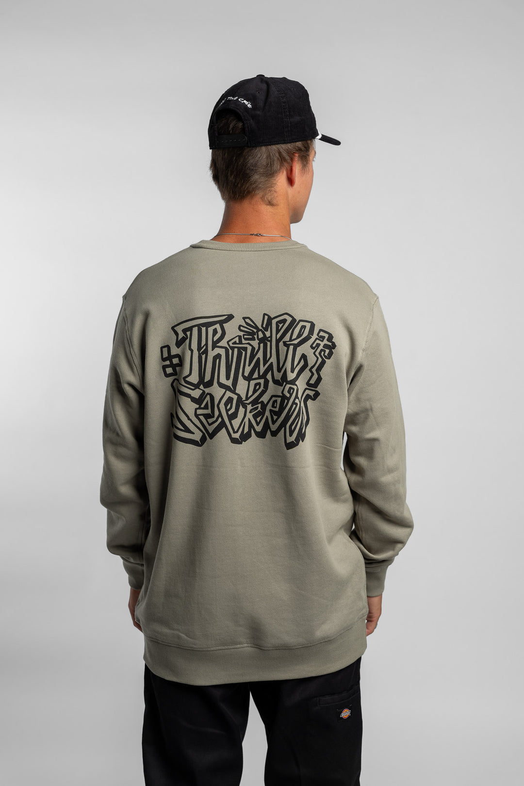 Person wearing eucalyptus crewneck with 'Thrill Seekers' scribe logo
